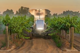 The Mini GUSS sprayer with a stainless steel body and vineyard attachment spraying in vineyard rows.