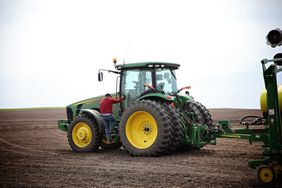 Farmer climbs in a John Deere tractor