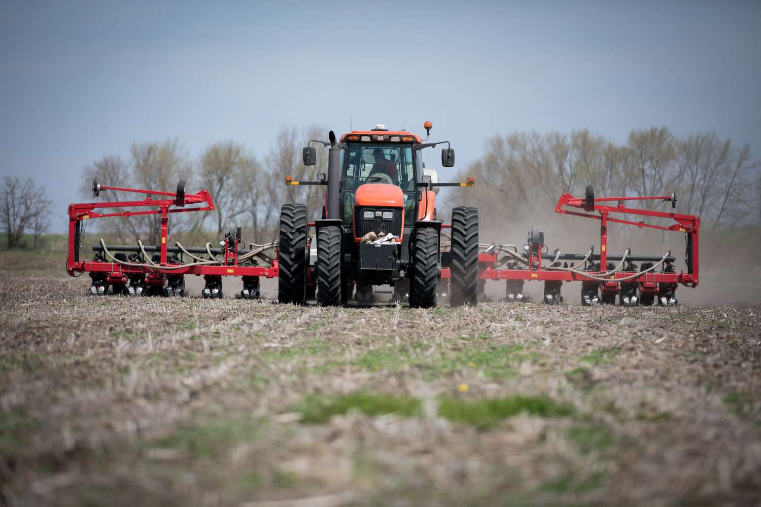 A red tractor pulling a red planter plants row crops at Felt Family Farms in Iowa