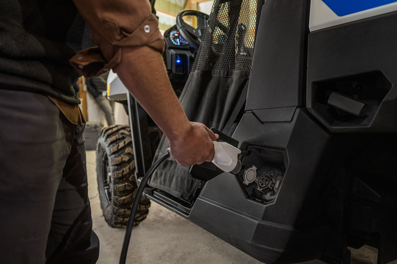 A man plugs in a Polaris Ranger XP Kinetic inside a shop