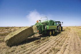 The L341R high-density large square baler dropping off a bale in the field.