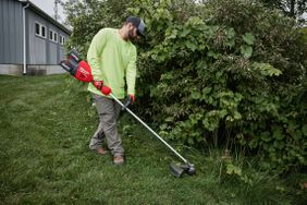 A man using the Milwaukee M18 dual battery string trimmer