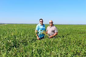 Kyle Durham and his father, David Durham, stand in one of their soybean fields