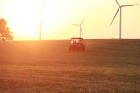 A UTV rides across a farm at sunset.