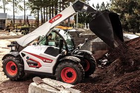 A white Bobcat TL723 telehandler on the jobsite with its arm raised.