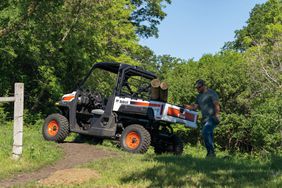 Farmer working on fence with Bobcat gas UTV