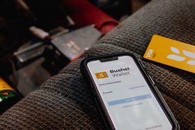 A phone using the Bushel app, and Bushel debit card beside it.