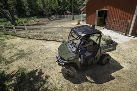 Green Polaris Ranger in a farm yard with a red barn