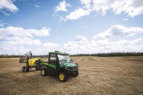 The John Deere Gator UTV pulling a sprayer in the field with the Starfire AutoTrac system equipped on the roof.