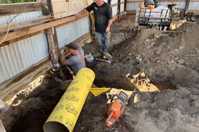 Construction workers repair a foundation beam in a polebarn.