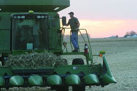 A farmer and his son stand on a combine.