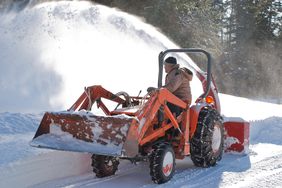 Man on a tractor equipped with a snow blower