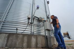 A farmer checks on the GSI GrainVue tool attached to the side of a grain bin.cf