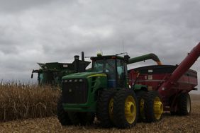 A grain cart catches a load of corn from a combine.