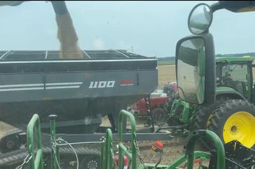 Matt Miles fills a gray grain cart with harvested soybeans