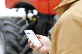 A man holding a phone with the Bushel Farm app on the screen