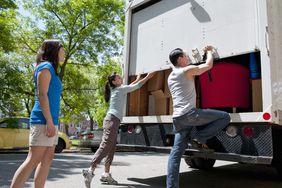 Young adults closing the back of a packed moving truck