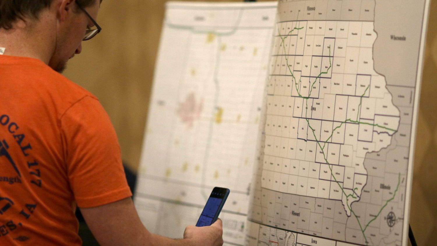 Man-looking-at-phone-Iowa-map-carbon-pipeline