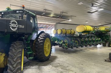 A John Deere tractor and planter sit in a farm shop