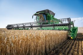 A John Deere T6 800 from the front, harvesting grain in a field.