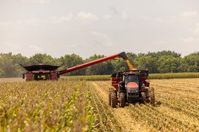 A Case IH combine unloading into a Raven Cart Automation-powered tractor pulling a grain cart.