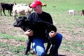 A young farmer holding a calf.