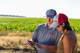 Two people in a field working off of an iPad.